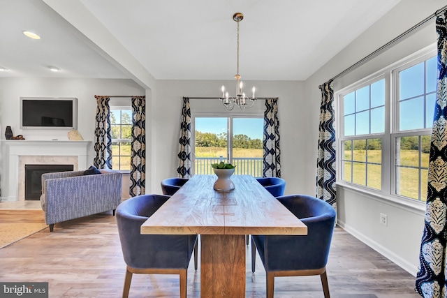 dining room featuring baseboards, a fireplace, an inviting chandelier, and wood finished floors