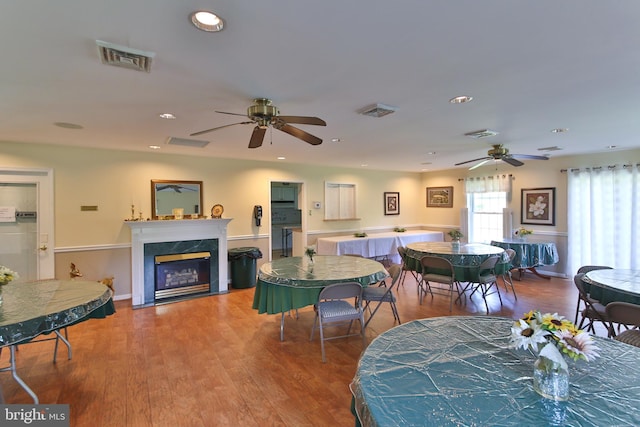 dining space featuring ceiling fan, a high end fireplace, and hardwood / wood-style flooring