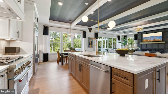 kitchen featuring hanging light fixtures, appliances with stainless steel finishes, a chandelier, white cabinetry, and sink