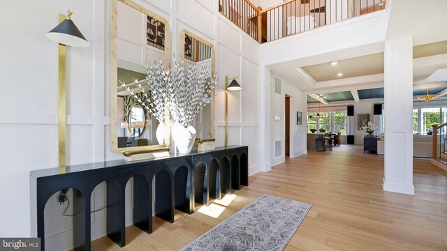 foyer entrance with visible vents, a towering ceiling, ornate columns, and wood finished floors