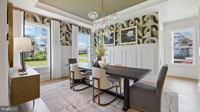 dining space featuring plenty of natural light, a raised ceiling, light hardwood / wood-style flooring, and a chandelier