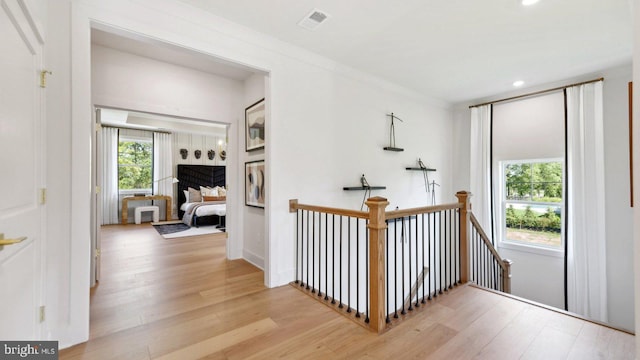 hall with ornamental molding and light hardwood / wood-style flooring