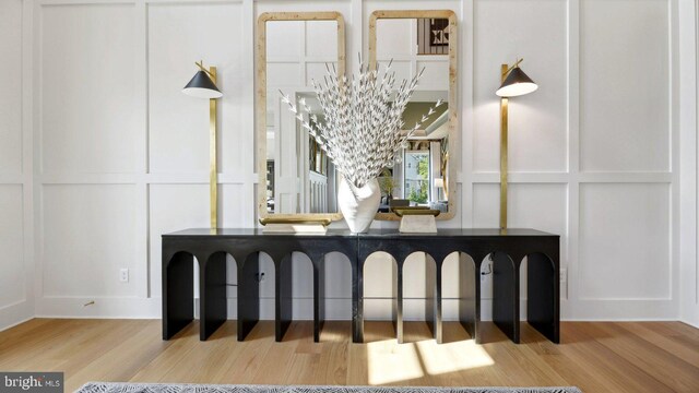 bathroom featuring a notable chandelier, a decorative wall, and wood finished floors