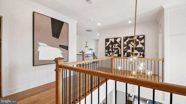 hallway with crown molding, hardwood / wood-style floors, and a chandelier