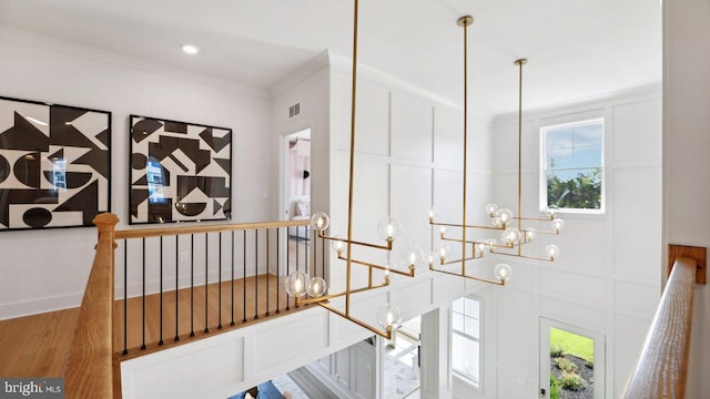 corridor featuring ornamental molding, a chandelier, and hardwood / wood-style floors