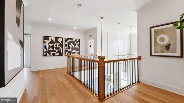 corridor with light wood-type flooring and crown molding