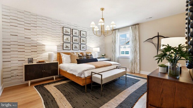 bedroom with light hardwood / wood-style flooring and a chandelier