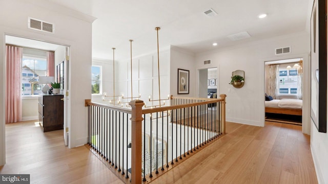 hallway with light wood-type flooring and crown molding