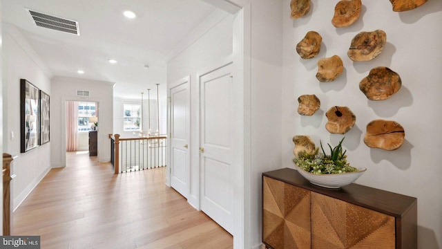 hallway with light wood-type flooring and ornamental molding