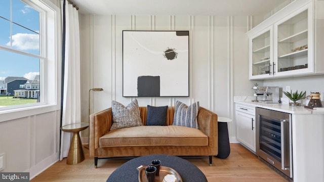 living room with beverage cooler, indoor bar, and light hardwood / wood-style floors