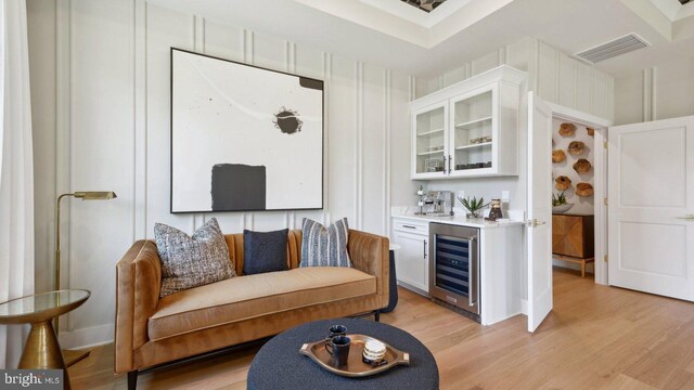 living room featuring bar area, beverage cooler, and light hardwood / wood-style floors