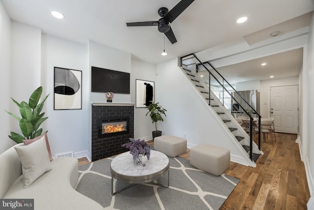 living room with ceiling fan, hardwood / wood-style floors, and a tile fireplace