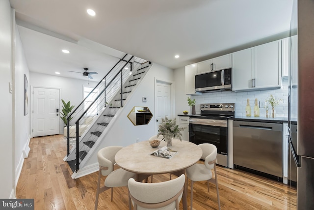 kitchen with stainless steel appliances, light hardwood / wood-style flooring, white cabinetry, tasteful backsplash, and ceiling fan