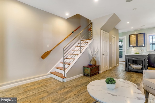 living room with wood-type flooring, stairs, and baseboards