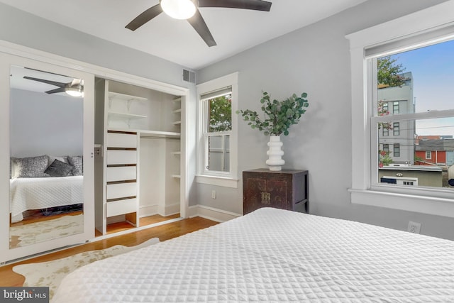 bedroom with multiple windows, wood finished floors, visible vents, and a ceiling fan