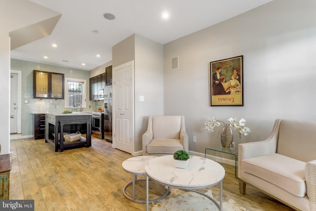 living area with recessed lighting, visible vents, light wood-style flooring, and baseboards