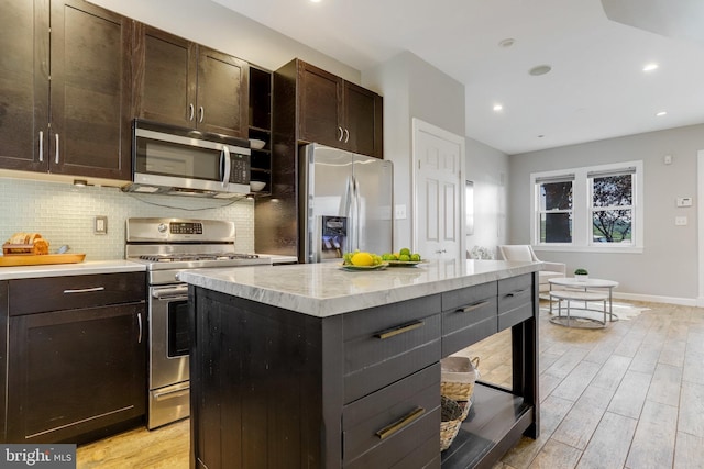 kitchen with appliances with stainless steel finishes, light wood-type flooring, backsplash, and recessed lighting