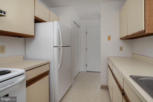 kitchen with cream cabinetry, white appliances, and sink