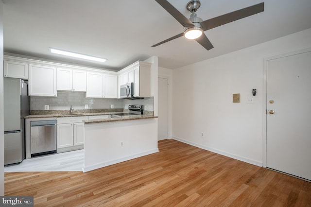 kitchen with white cabinets, stainless steel appliances, ceiling fan, and light hardwood / wood-style floors