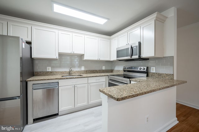 kitchen with white cabinets, light wood-type flooring, stainless steel appliances, and sink