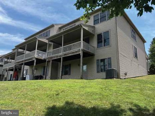 back of house featuring a balcony, central air condition unit, and a yard