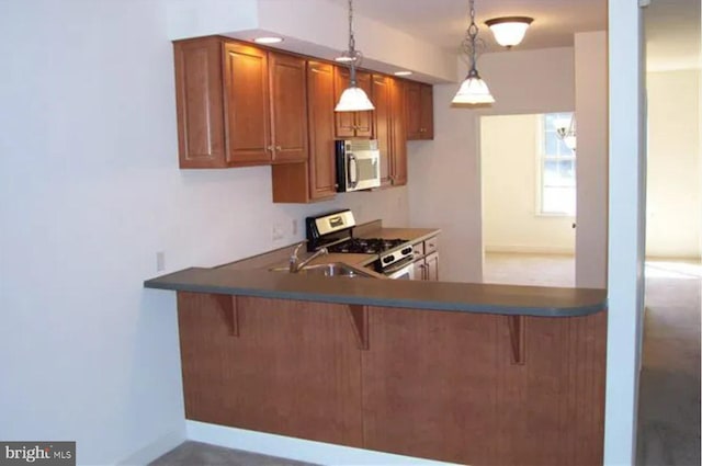 kitchen featuring a kitchen breakfast bar, sink, decorative light fixtures, kitchen peninsula, and stainless steel appliances