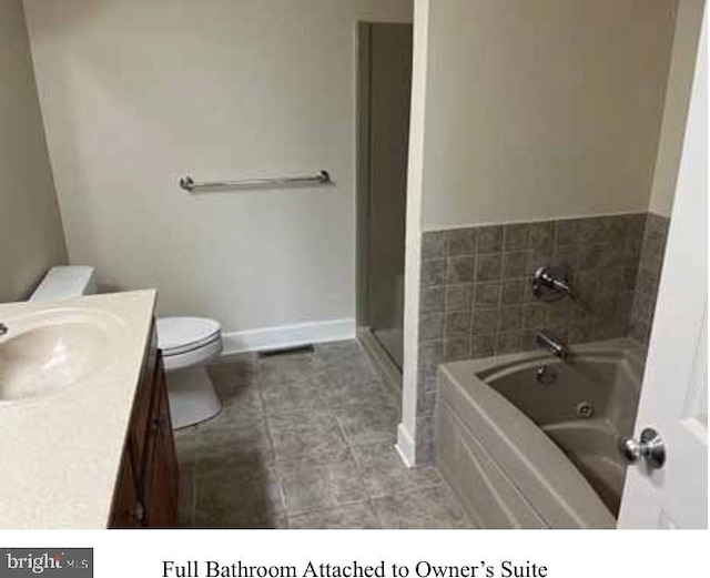 bathroom featuring tile patterned flooring, toilet, a tub to relax in, and vanity