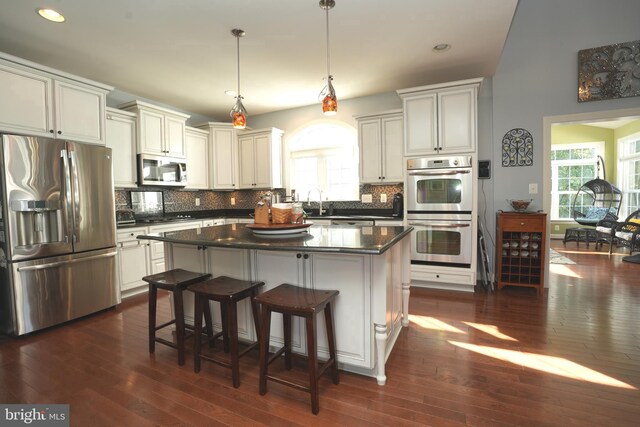 kitchen featuring a breakfast bar area, a center island, stainless steel appliances, pendant lighting, and backsplash