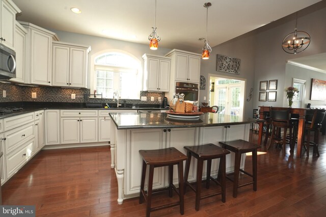 kitchen with a kitchen island, dark countertops, a sink, and oven