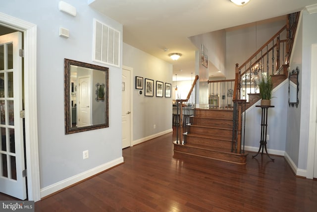 interior space with dark wood-style floors, visible vents, stairway, and baseboards