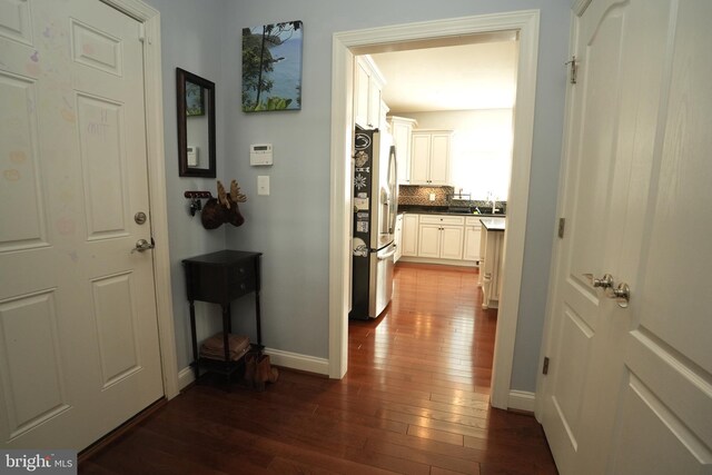 hall featuring dark wood-style flooring and baseboards