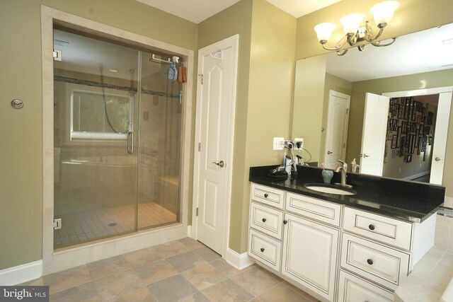 full bath with a chandelier, a stall shower, vanity, and baseboards