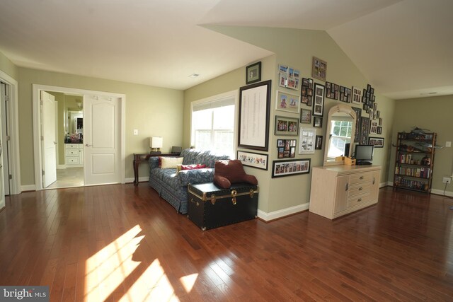 living room featuring a healthy amount of sunlight, vaulted ceiling, baseboards, and dark wood finished floors