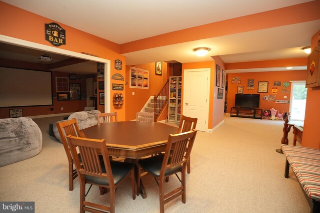 carpeted dining area with stairway and baseboards