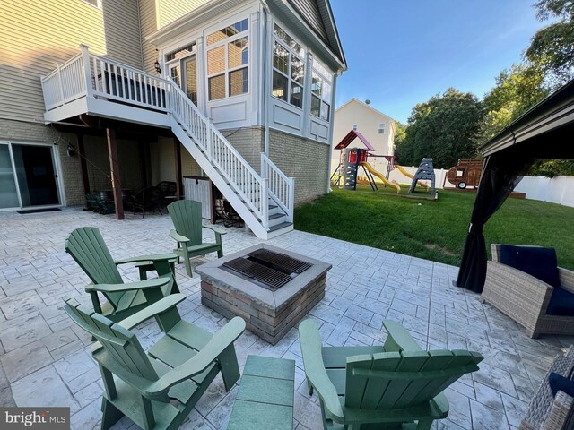 view of patio with an outdoor fire pit, stairs, and a playground