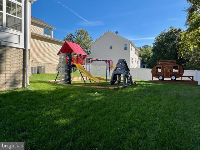 view of jungle gym with an outbuilding, a storage unit, a lawn, and fence