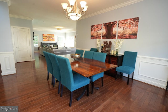 dining area with dark wood-style floors, a wainscoted wall, crown molding, and an inviting chandelier