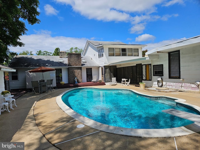 view of swimming pool featuring a diving board and a patio area