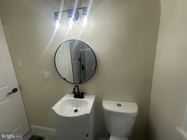 half bathroom with toilet, visible vents, vanity, and baseboards