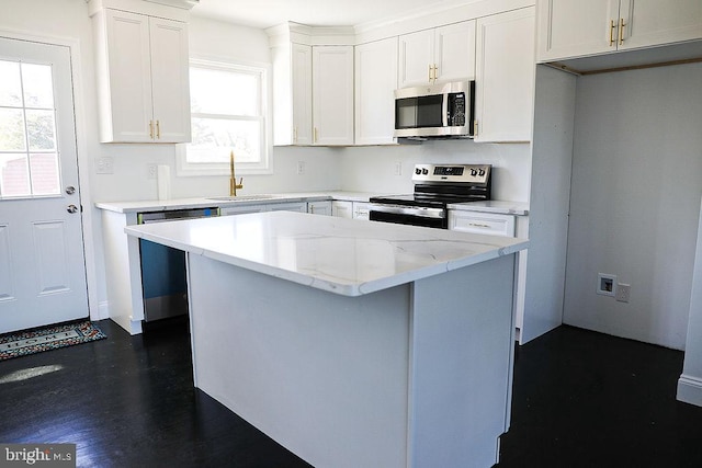 kitchen with a kitchen island, a sink, white cabinetry, appliances with stainless steel finishes, and a wealth of natural light