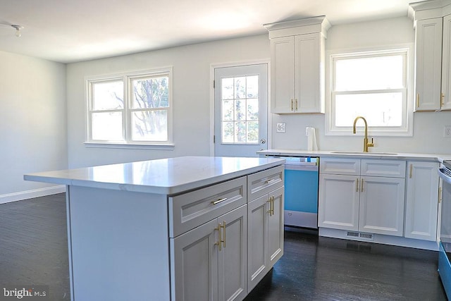 kitchen featuring light countertops, white cabinets, a kitchen island, a sink, and dishwasher