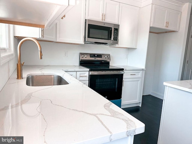 kitchen with stainless steel appliances, white cabinets, a sink, and light stone counters