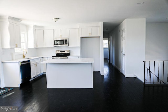 kitchen with a sink, white cabinetry, a healthy amount of sunlight, appliances with stainless steel finishes, and a center island