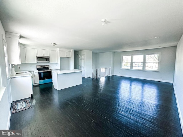 kitchen with stainless steel appliances, light countertops, open floor plan, white cabinetry, and a kitchen island