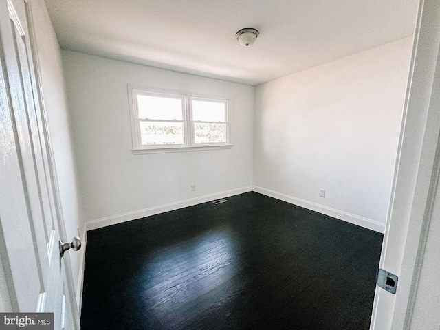 unfurnished room with dark wood-style flooring and baseboards