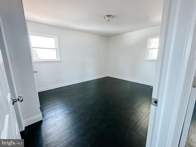 spare room featuring dark wood-style flooring and baseboards