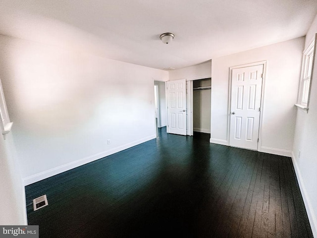 unfurnished bedroom featuring a closet, visible vents, dark wood finished floors, and baseboards