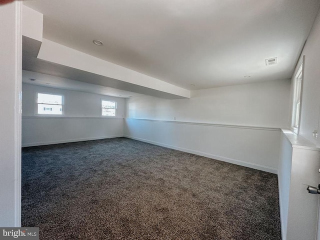 unfurnished room featuring visible vents, dark carpet, and baseboards