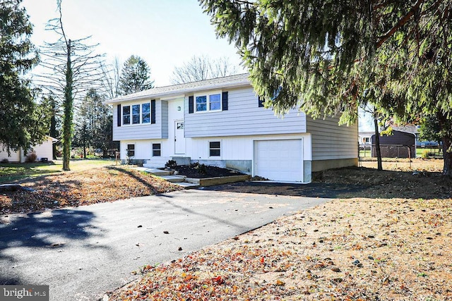 raised ranch with aphalt driveway and an attached garage