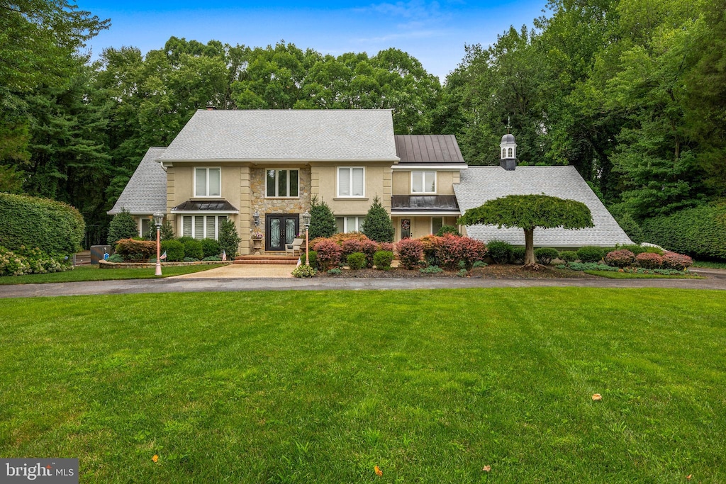 view of front of house featuring stone siding, aphalt driveway, and a front lawn